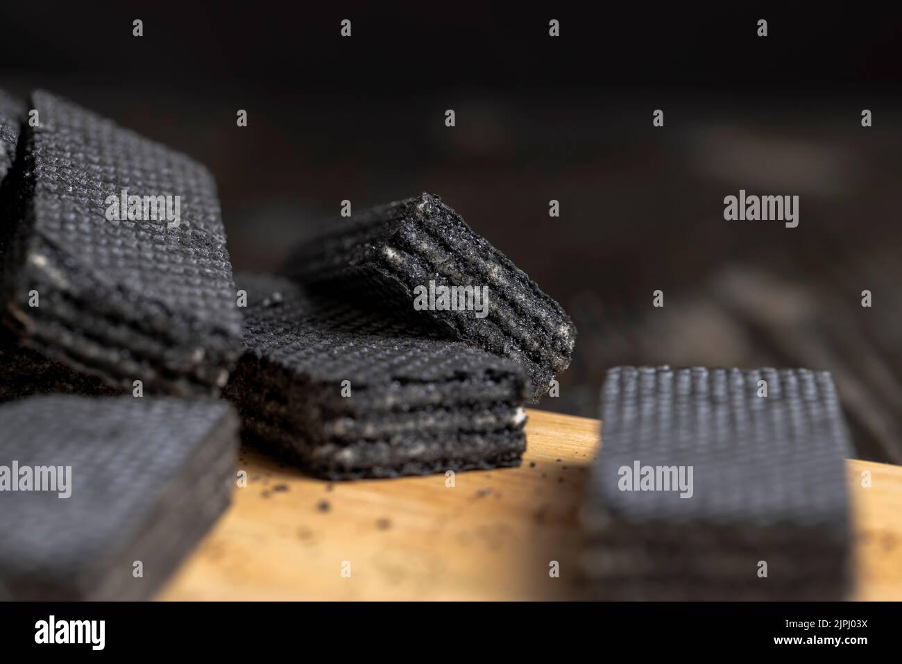 sweet dessert black waffles with creamy filling inside, laid out on a board dessert black crispy fresh waffles with layers of creamy filling Stock Photo