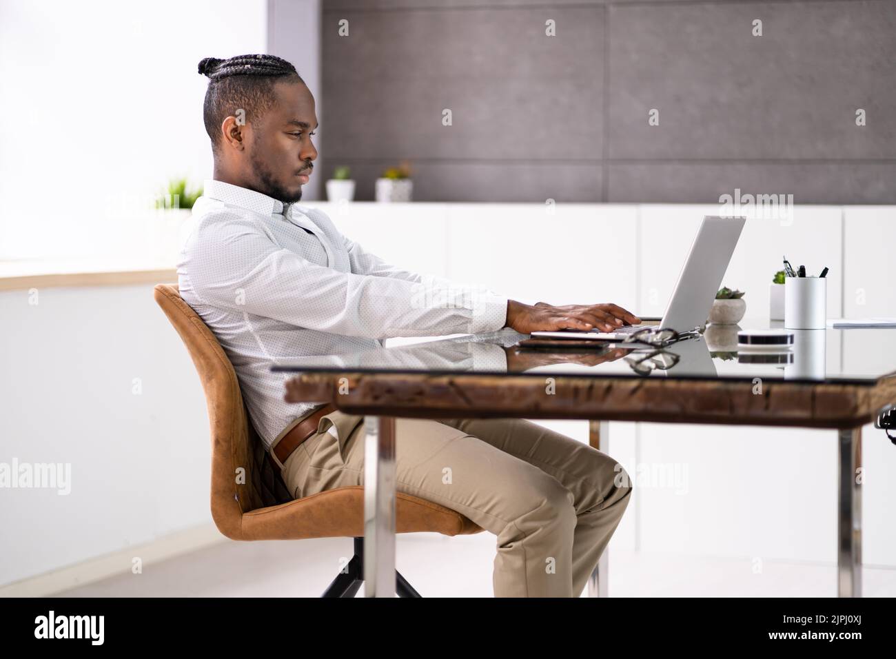 African Man Bad Posture Working Typing At Desk Stock Photo