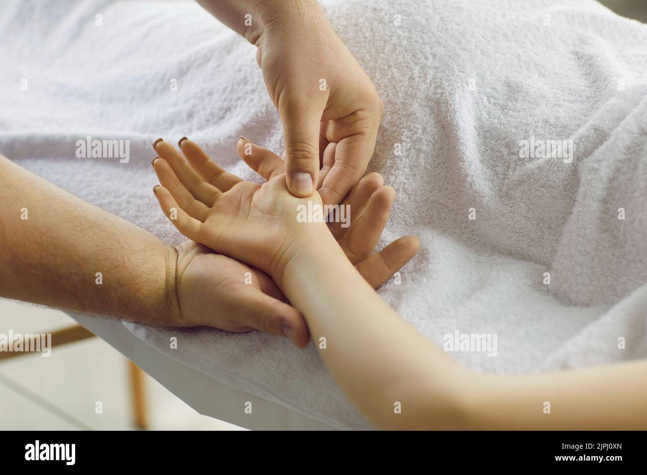 Professional in acupressure and reflexology massaging points on young woman's hand Stock Photo