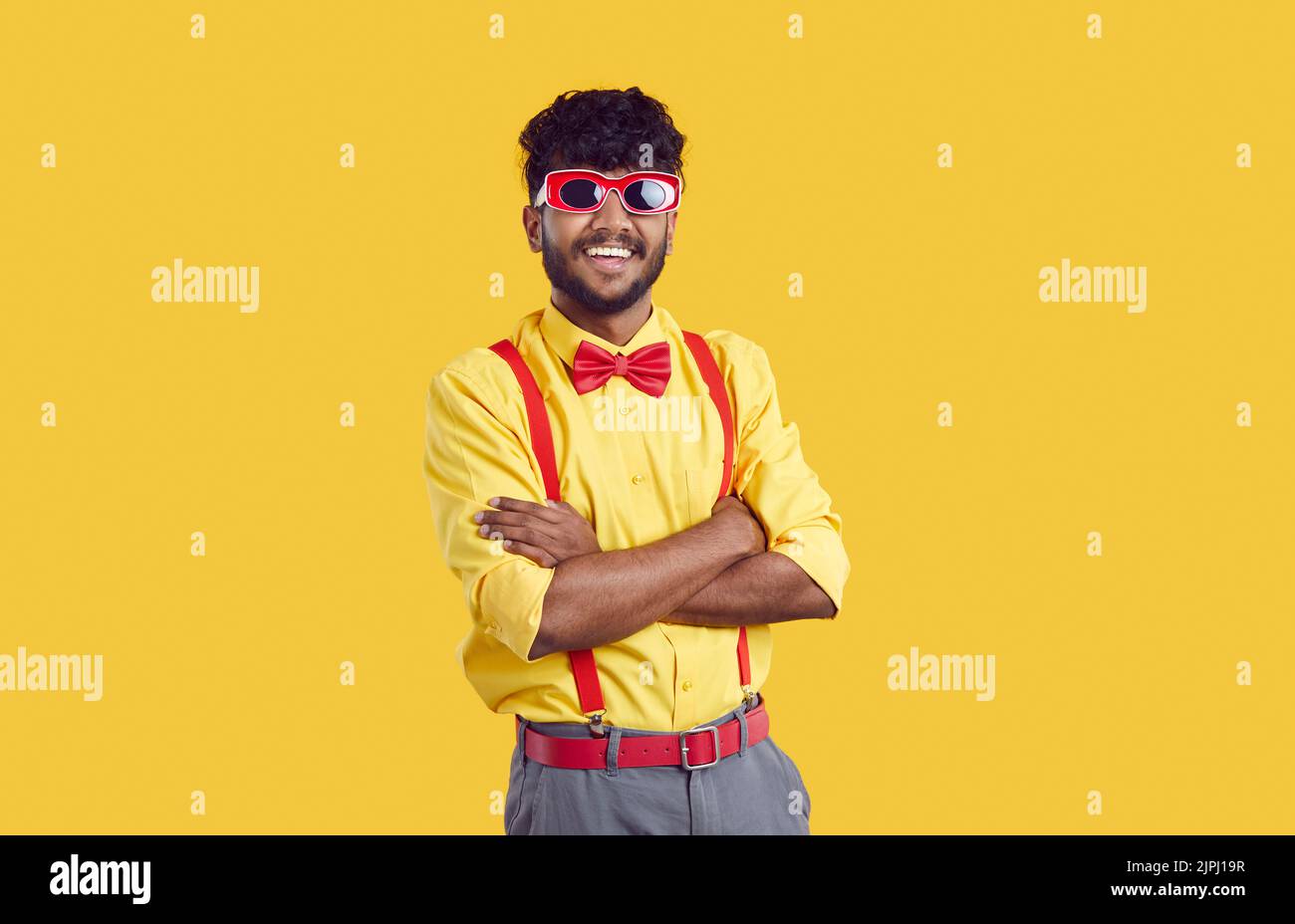 Funny young Indian man in glasses for party smiling with arms crossed