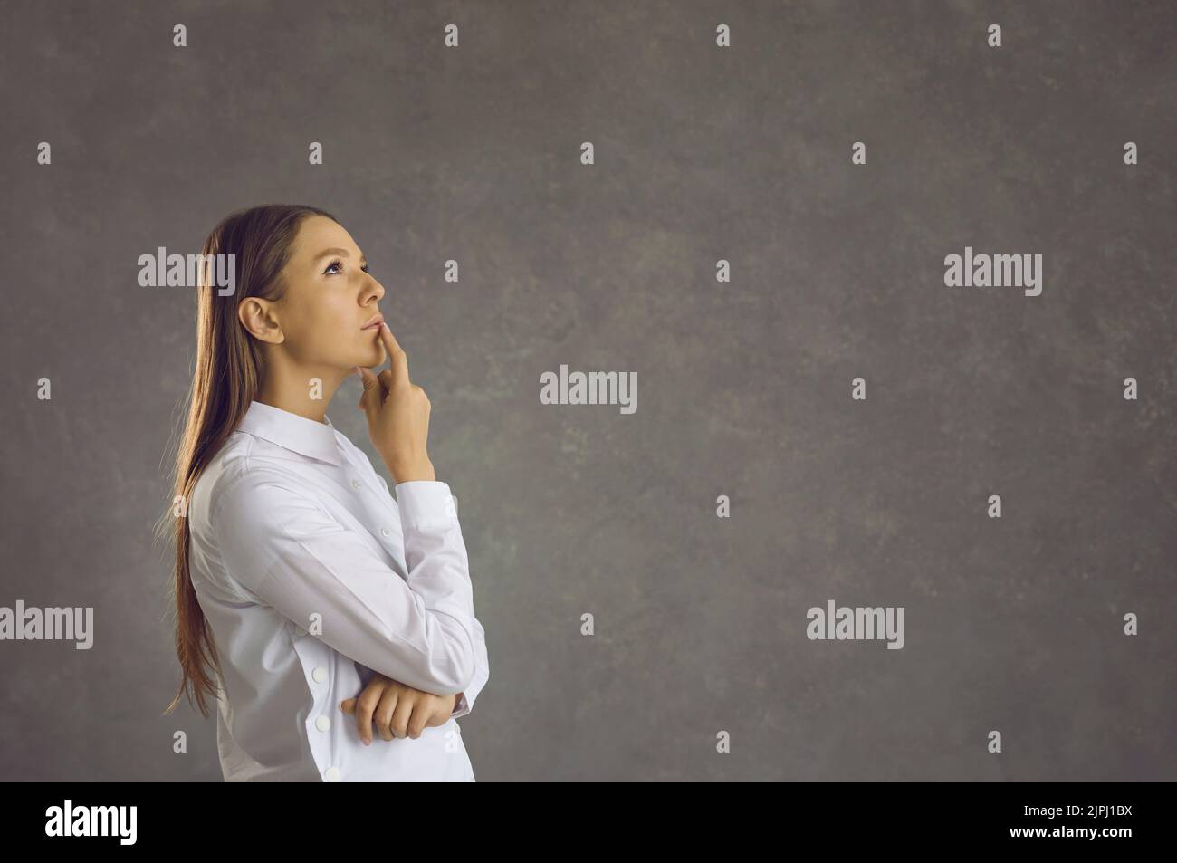 Young businesswoman thinking and doubting standing on grey copy space background Stock Photo