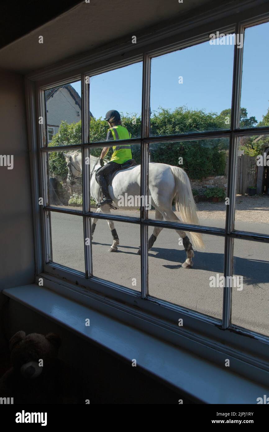 Horse rider on the road seen through window in village of Whitford, Devon Stock Photo Alamy