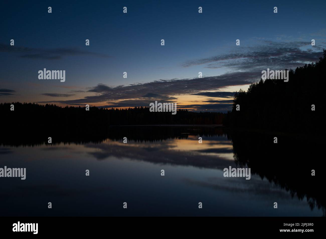 Summer night by the river, sky and clouds reflecting on water. Stock Photo