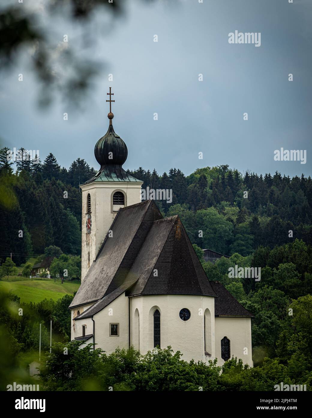 A vertical shot of a patriarchal church with forest and black clouds in the backgrond Stock Photo