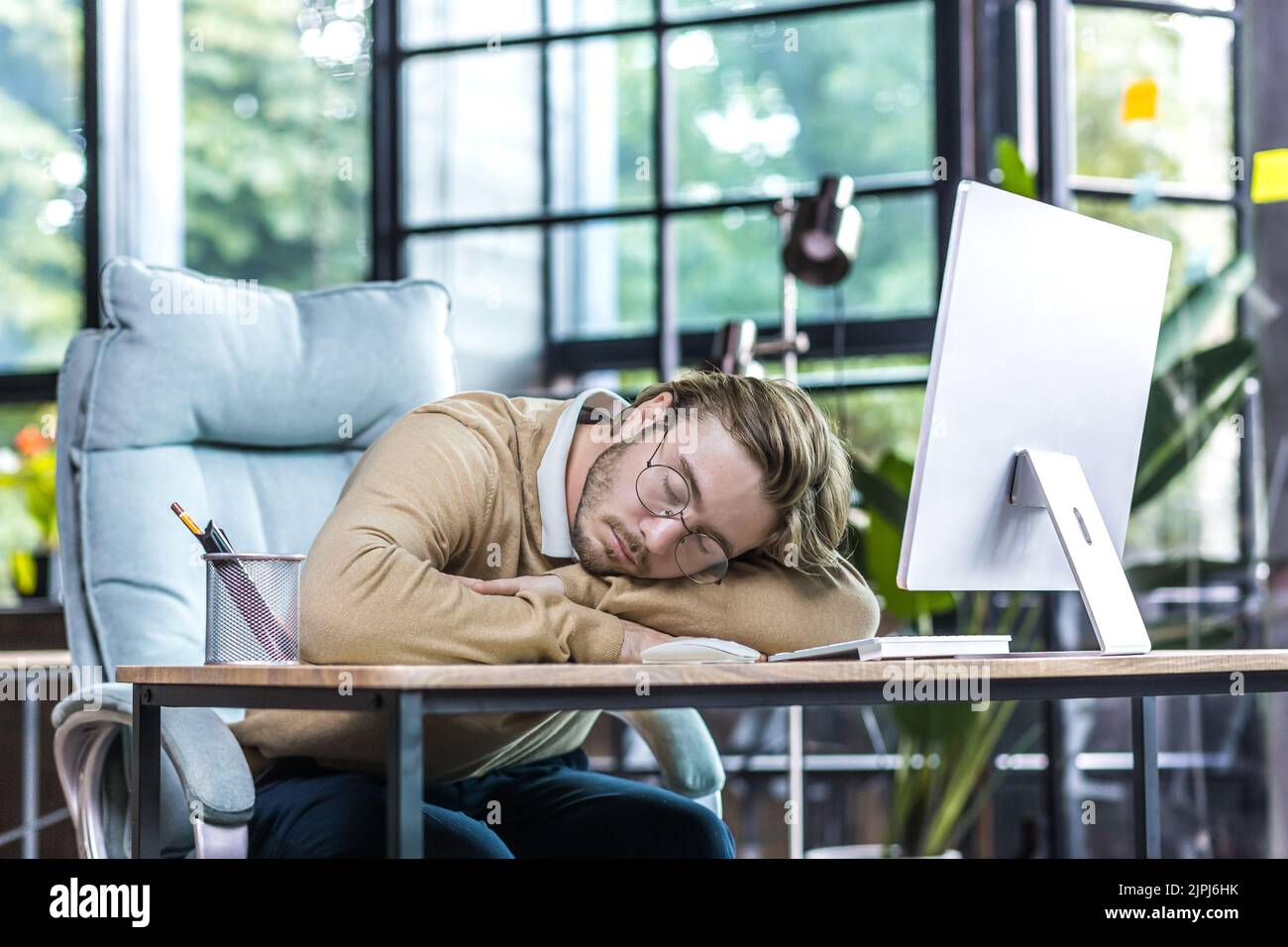 Young businessman resting in office, man in glasses sleeping on table