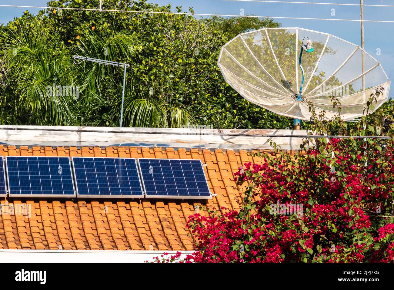 Roof of a house with photovoltaic energy plates and a satellite dish, in Brazil Stock Photo
