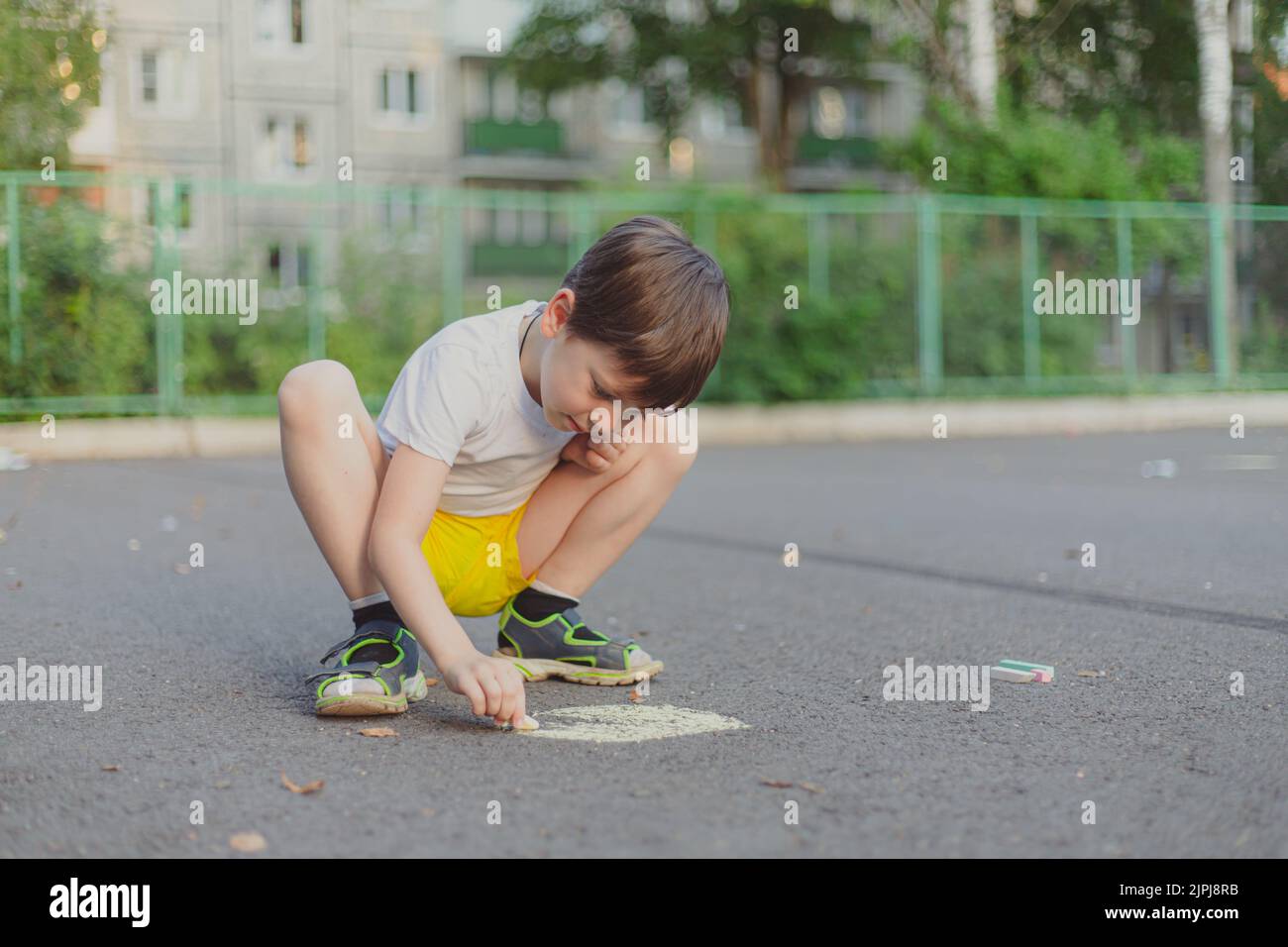 A boy draws a lifestyle with crayons on the asphalt . Children's ...