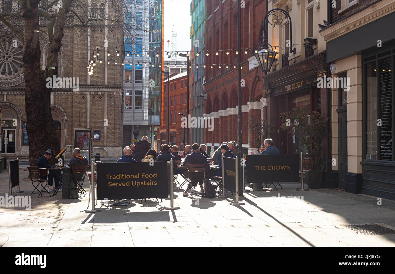 Patrons seated at terrace outside The Crown pub, New Oxford St, London