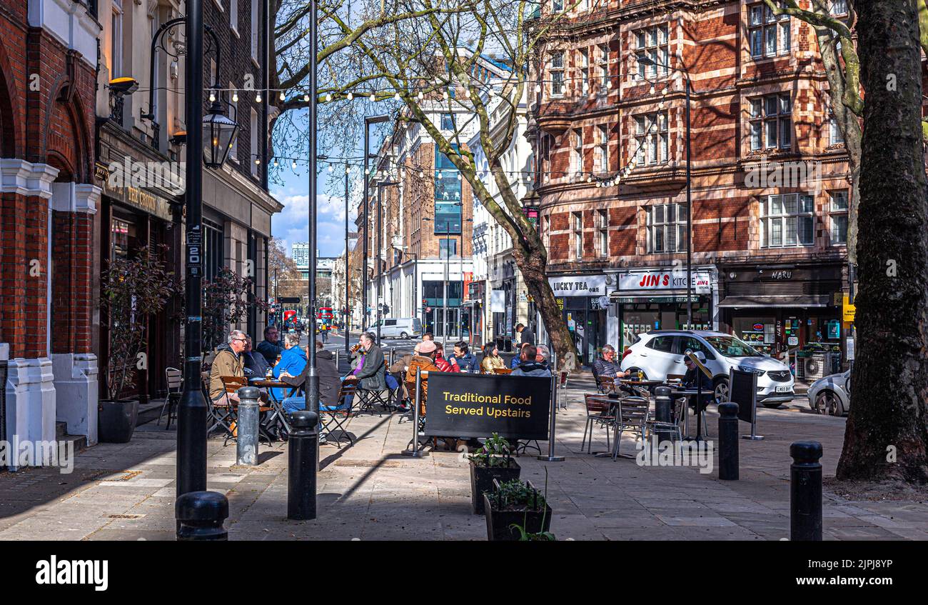Patrons seated at terrace outside The Crown pub, New Oxford St, London