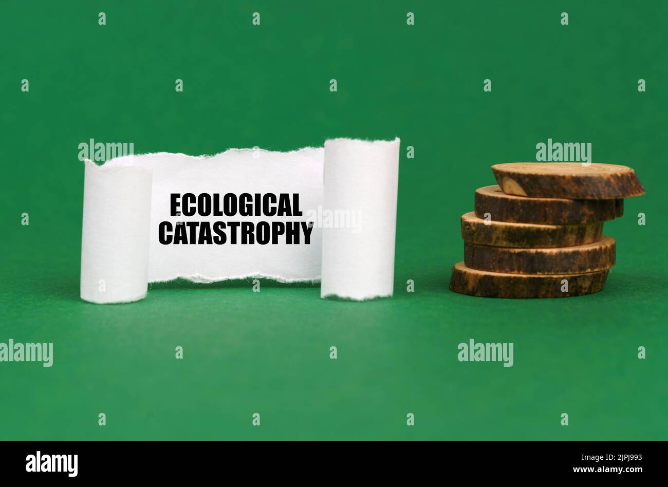 Ecological concept. On a green surface, wooden circles and a white paper plate with the inscription - Ecological catastrophy Stock Photo