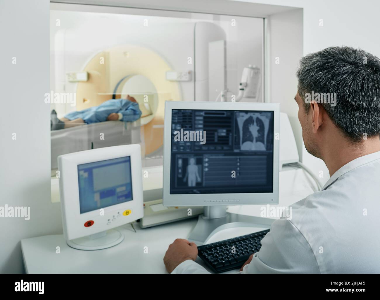 doctor radiologist running CT scan for patient's body lungs from control room. Computed Tomography Stock Photo