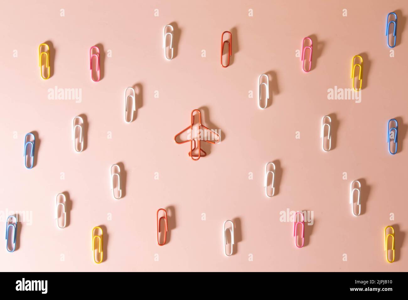 Colored paper clips on white background and airplane take off, forward movement concept Stock