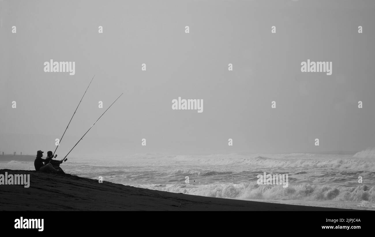 The silhouettes of two men fishing by the sea Stock Photo - Alamy