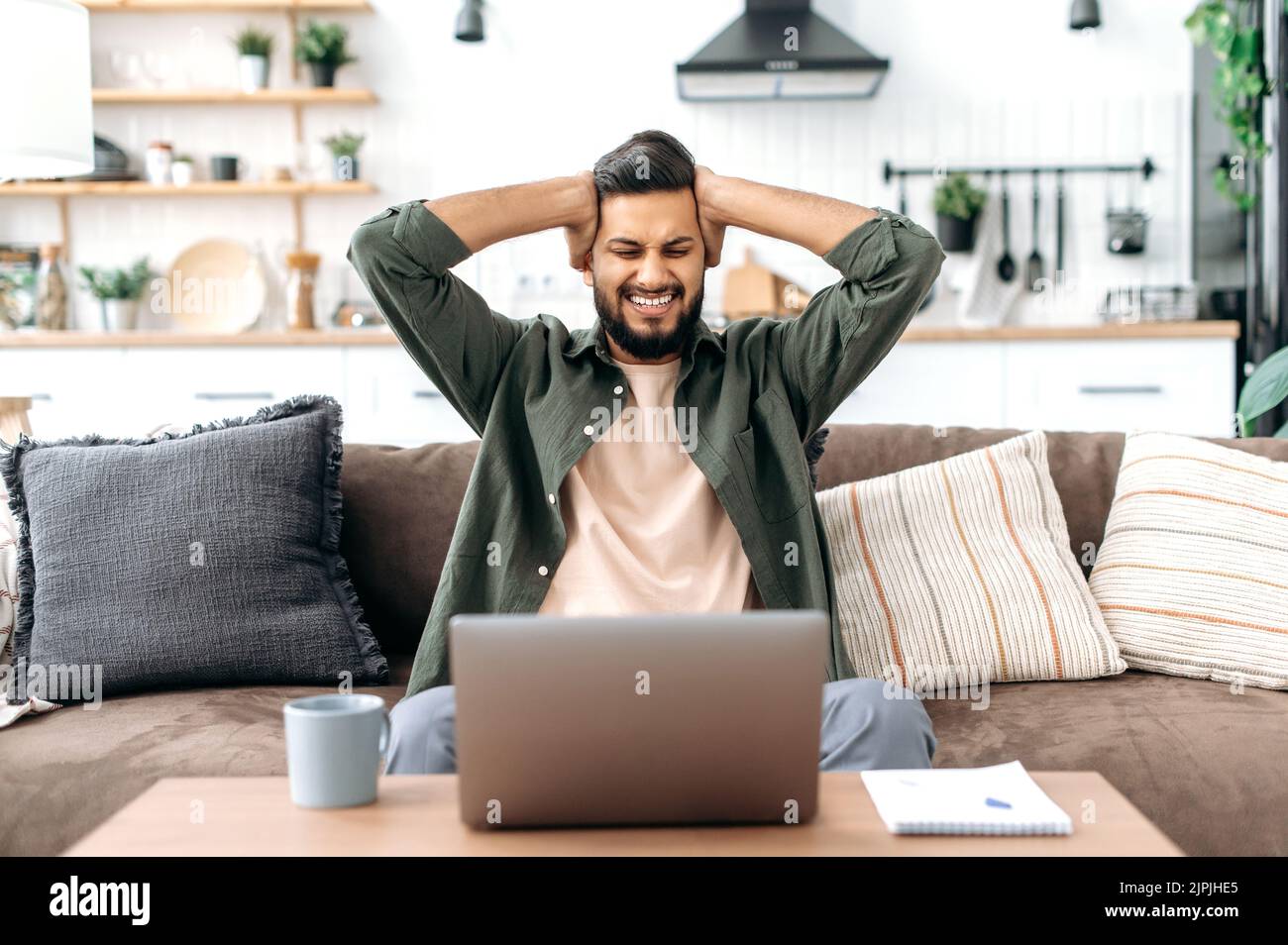 Shocked confused indian or arabian young man, freelancer, designer, looking surprised at laptop screen, stressed from the failure of a deal or project, read unexpected news, in desperation, annoyed Stock Photo