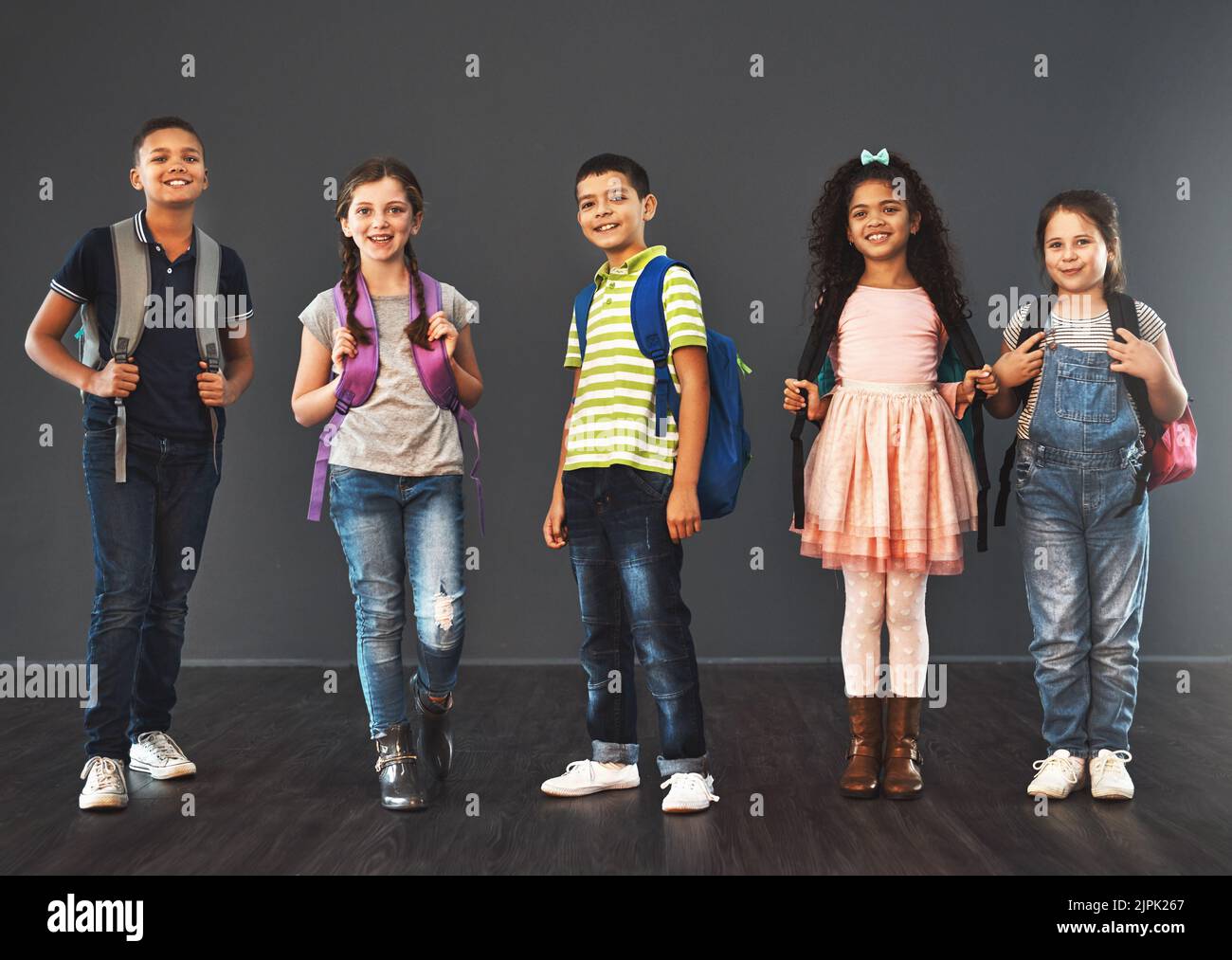 Today is the start of something new. Studio portrait of a diverse group of kids carrying their school backpacks against a gray background. Stock Photo