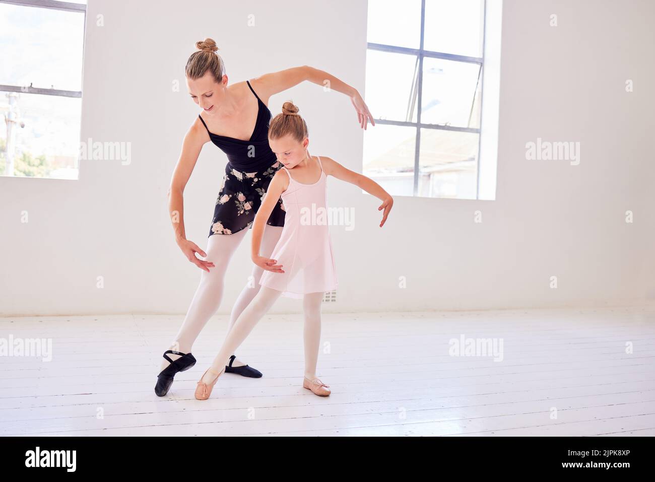 Ballet, elegance and dancing instructor teaching a little ballerina movement and posture at a dance studio. Teacher bonding with a child while Stock Photo