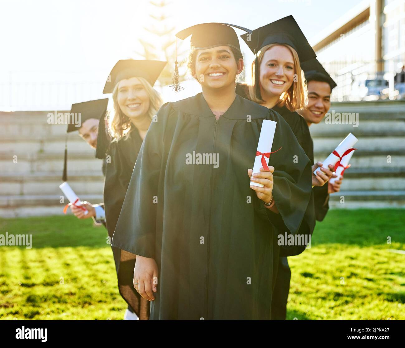 Diligence pays off. Portrait of a group of students holding their diplomas on graduation day. Stock Photo
