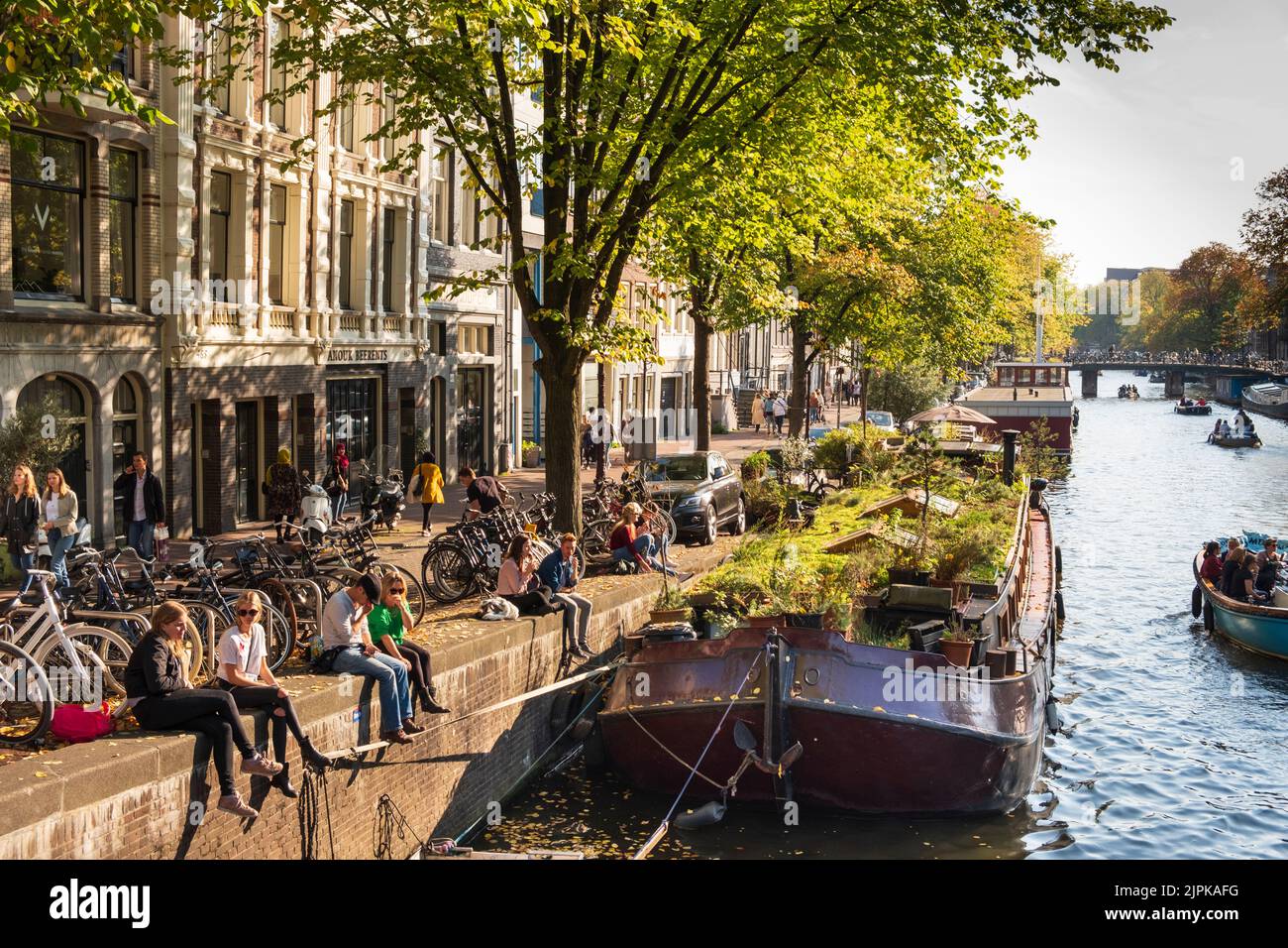 Young people relaxing with Row Homes and House Boats along The Prinsengracht Canal, Amsterdam, Holland Stock Photo