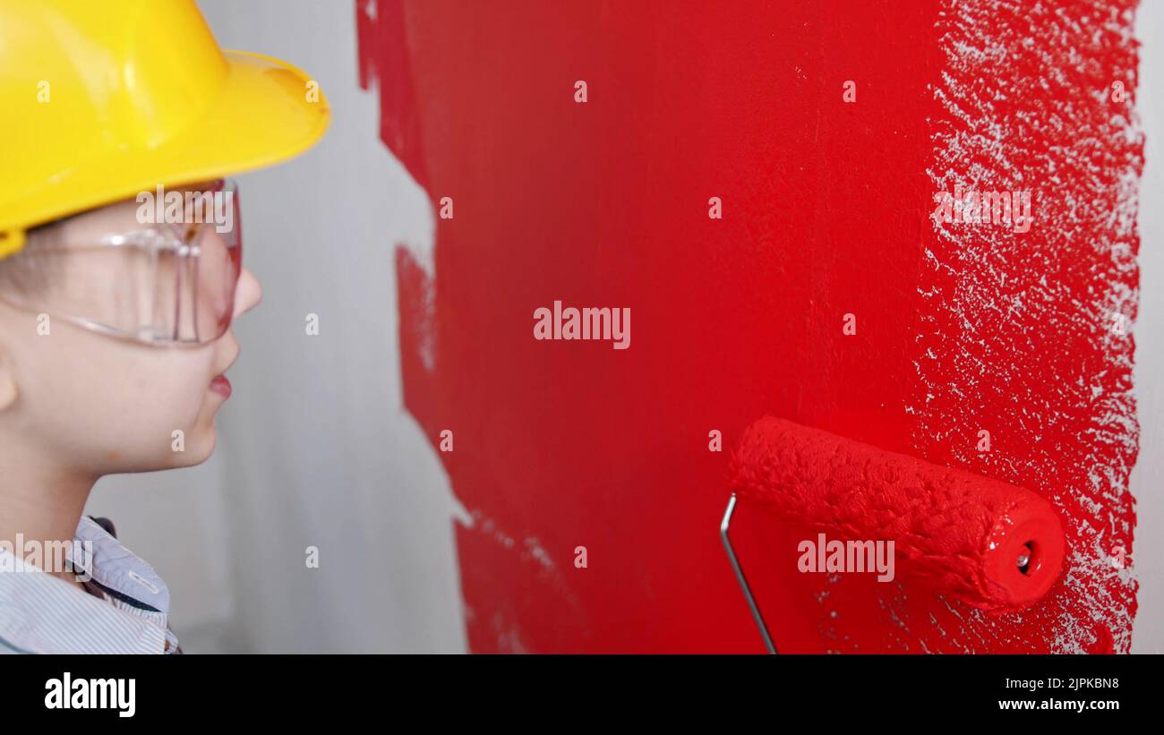 A little boy painting clear wall with red paint Stock Photo