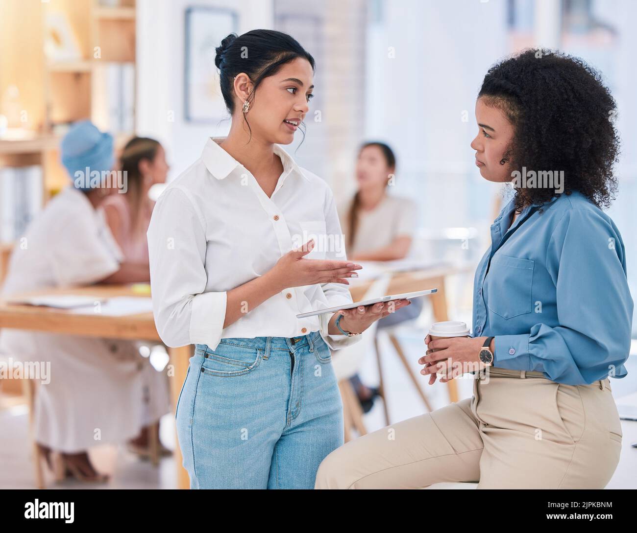 Empowered businesswomen working together on a project in the office. Female employees at work talking, collaborating, and brainstorming. Marketing Stock Photo