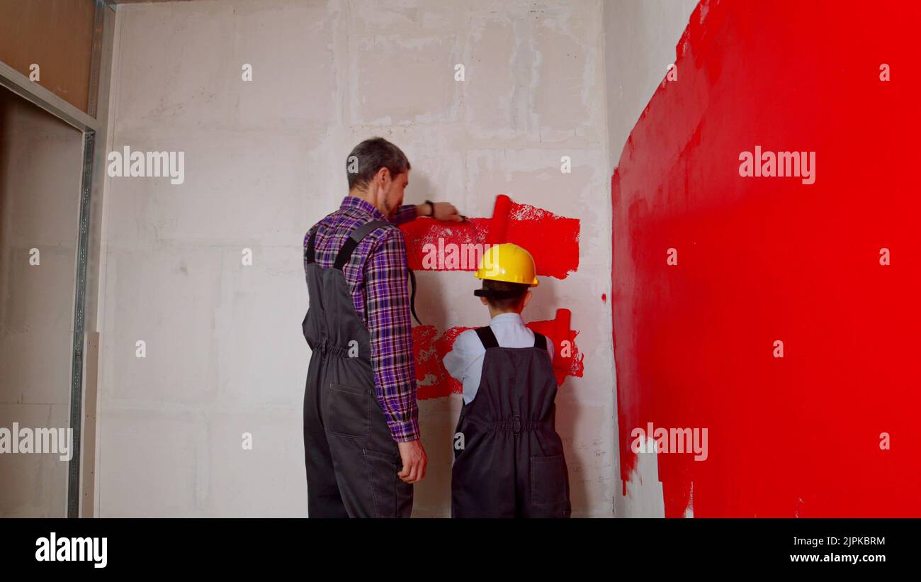 Apartment renovation - family of father and son covering wall in red paint Stock Photo