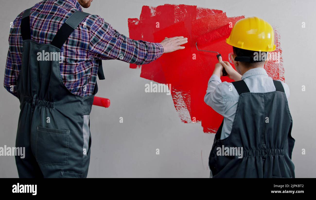 Apartment renovation - father and son covering wall in red paint in new apartment Stock Photo