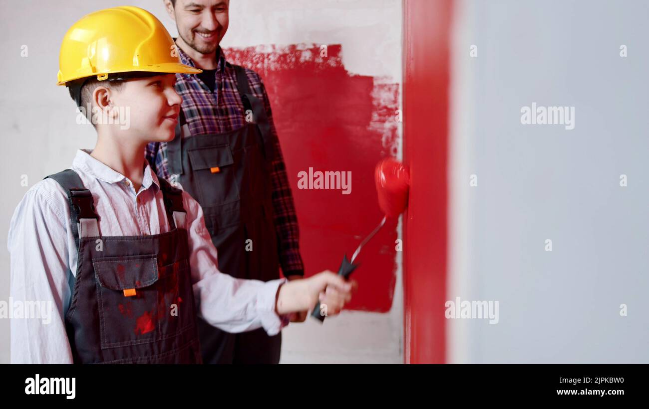 Repairing draft apartment - little boy and his father painting walls inside the room Stock Photo
