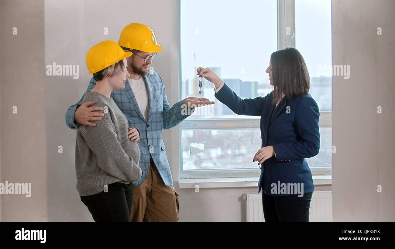 A real estate agent gives the keys to apartment to a young family Stock Photo