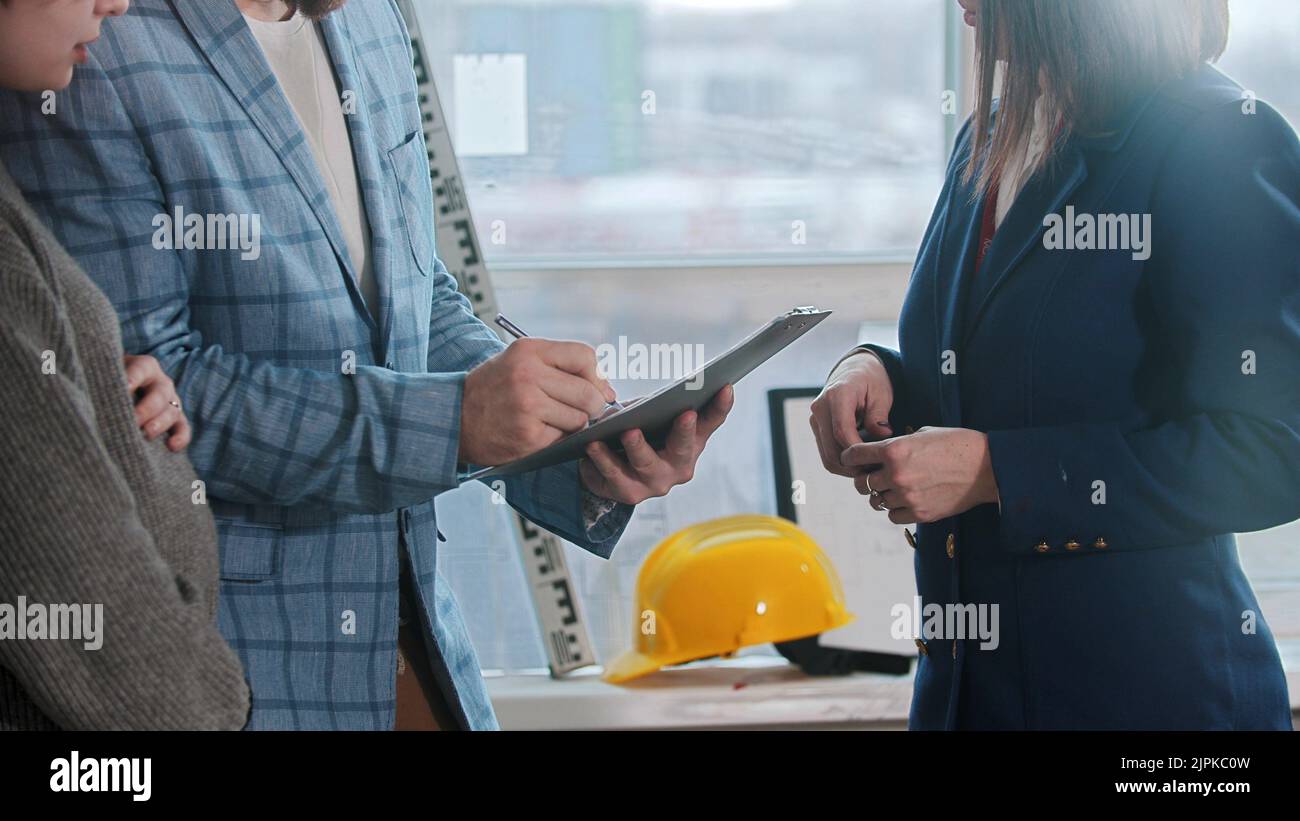 A pregnant woman with her husband in blue jacket signing papers for the apartment rental Stock Photo