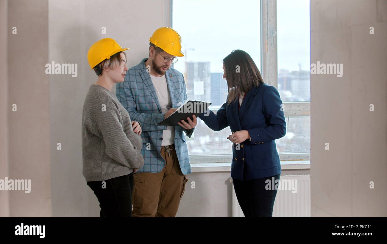 A pregnant woman with her bearded husband signing papers for the apartment rental Stock Photo