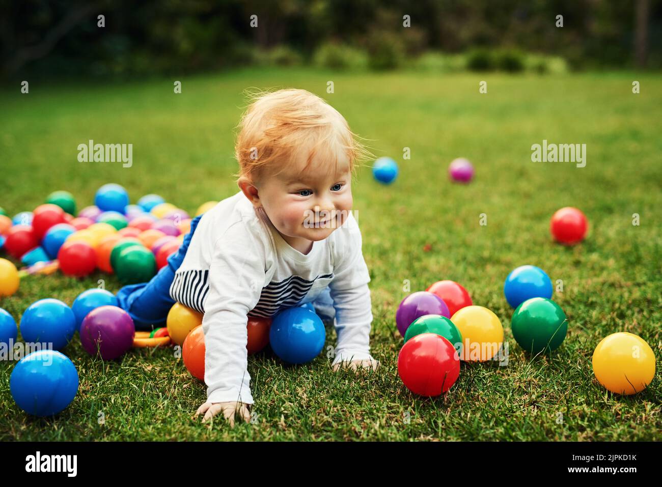Colourful balls here I come. an adorable little boy playing in the backyard. Stock Photo