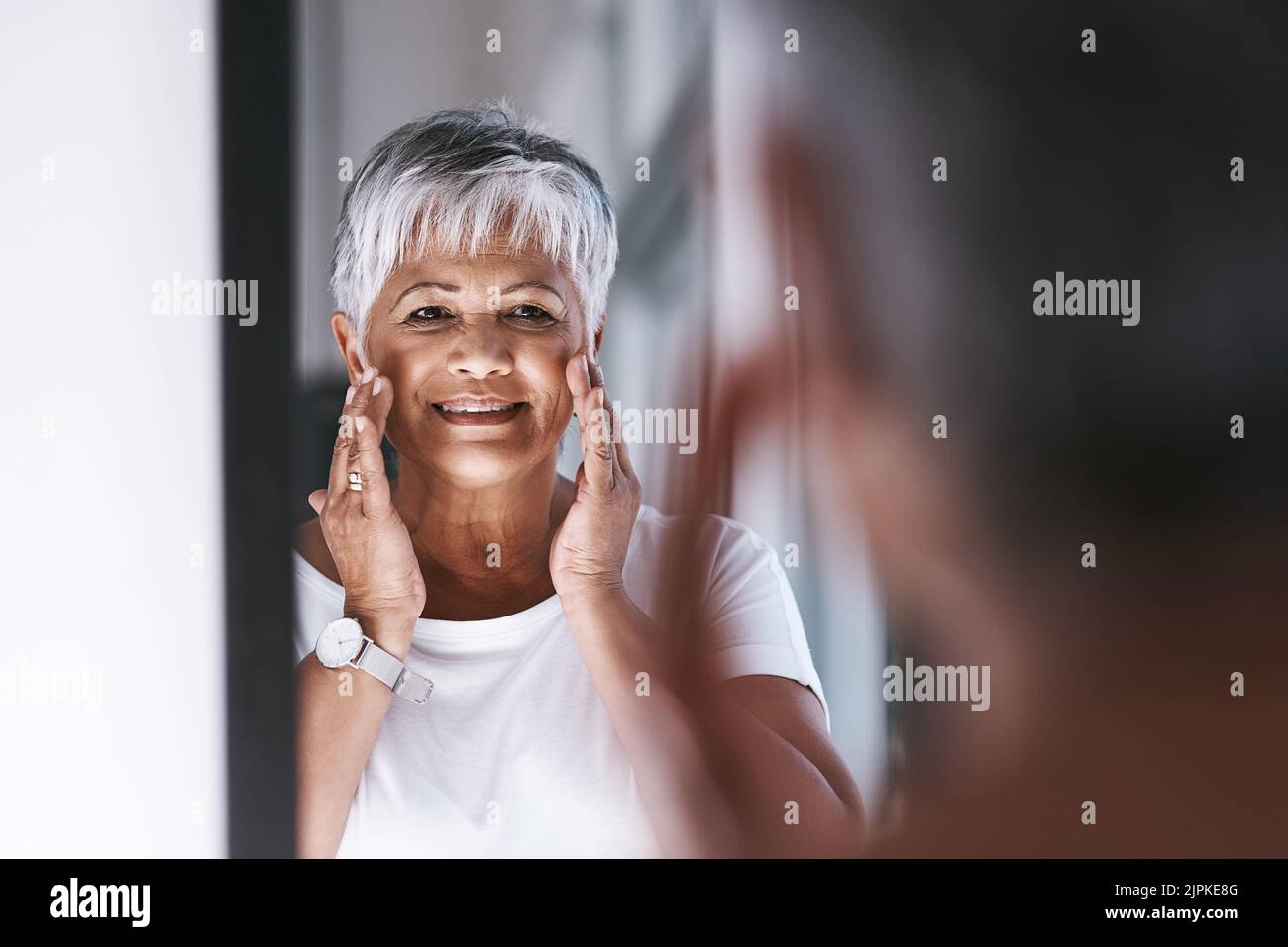 She is happy with how she looks. a cheerful mature woman touching her ...