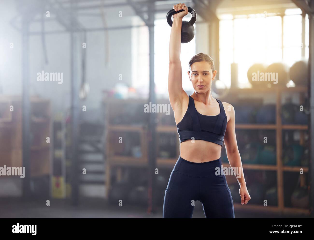 Strong, powerful woman doing kettlebell weight lift exercise, workout or training in wellness gym. Sports person holding or exercising with fitness Stock Photo