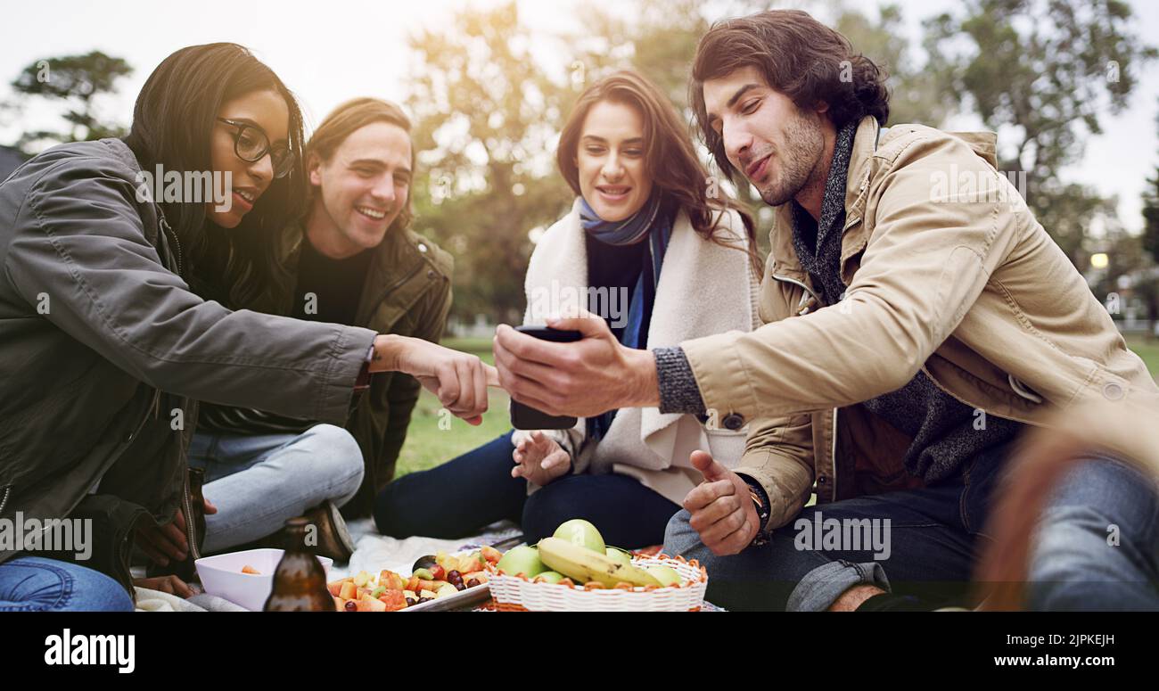 Reminiscing on old photos. young friends having a picnic outside. Stock Photo