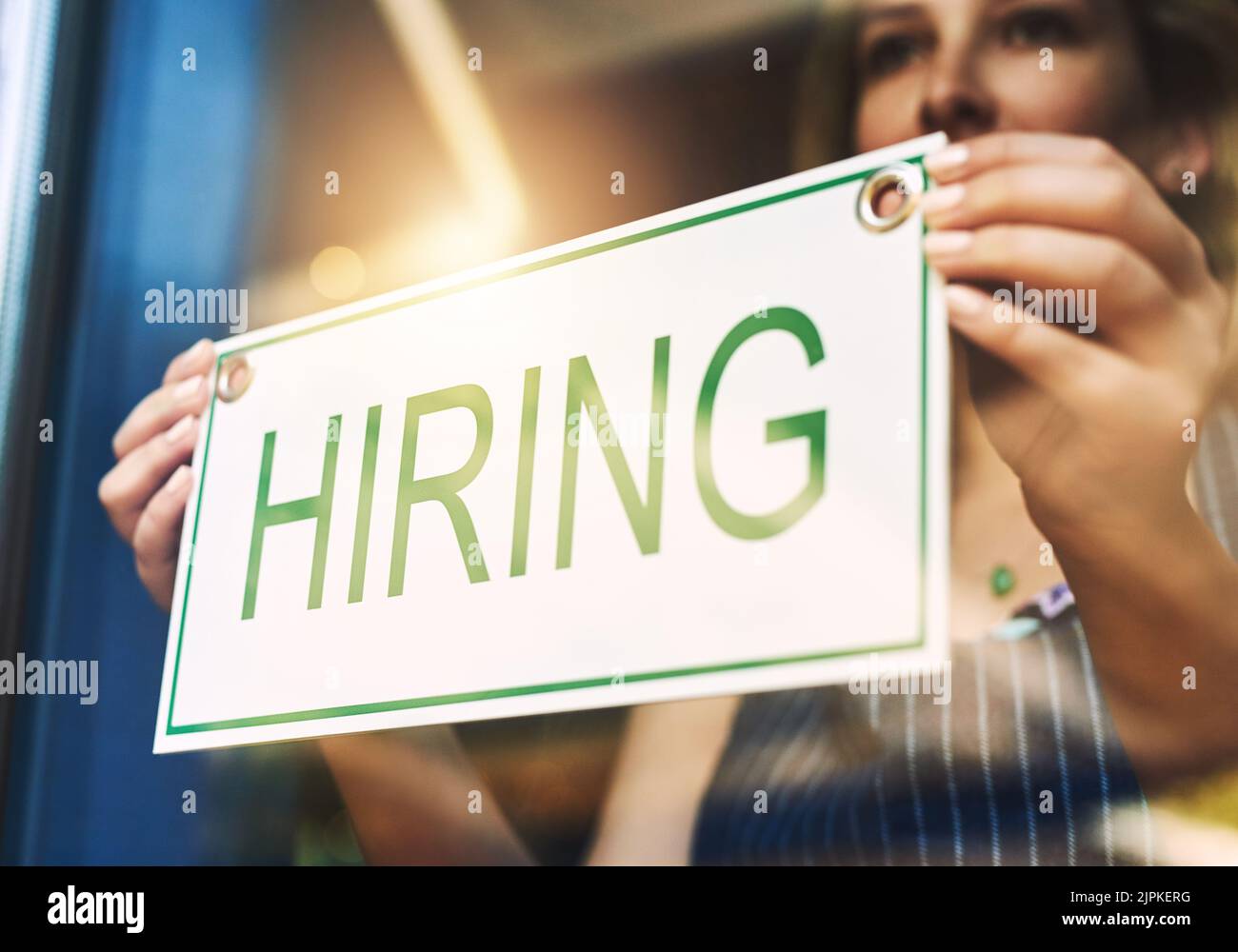 We now hiring, all is a woman putting up a hiring sign in a
