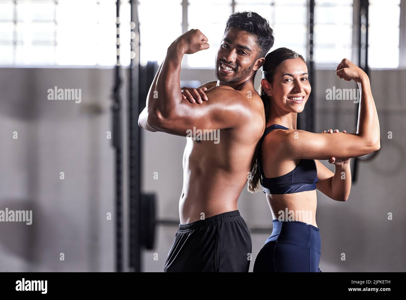 Fitness, flexing muscles and strong couple goals while doing exercise or training in a gym. Portrait of fit sports people, woman or man showing off Stock Photo
