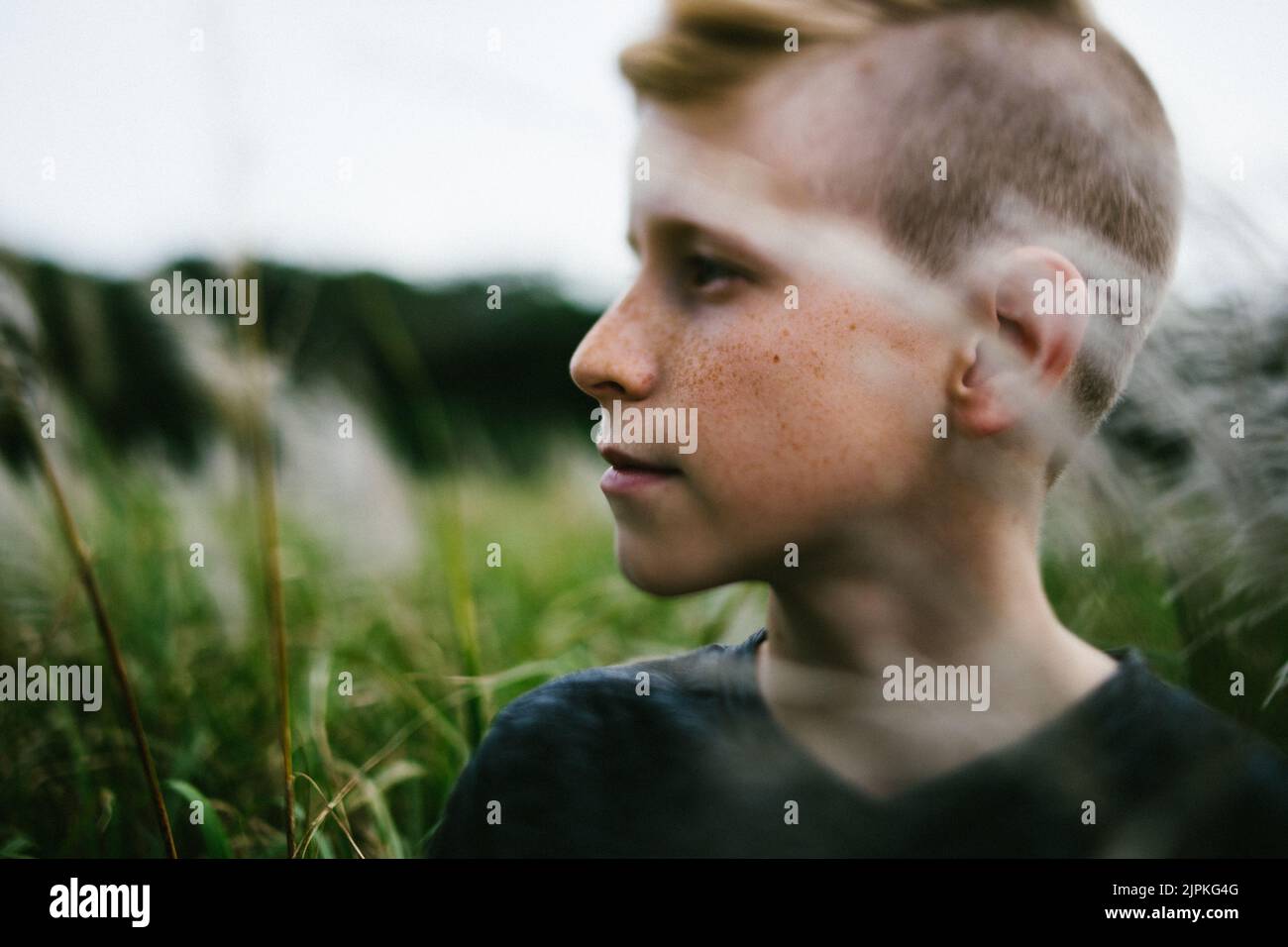Pre teenage boy outside in nature in grass field Stock Photo