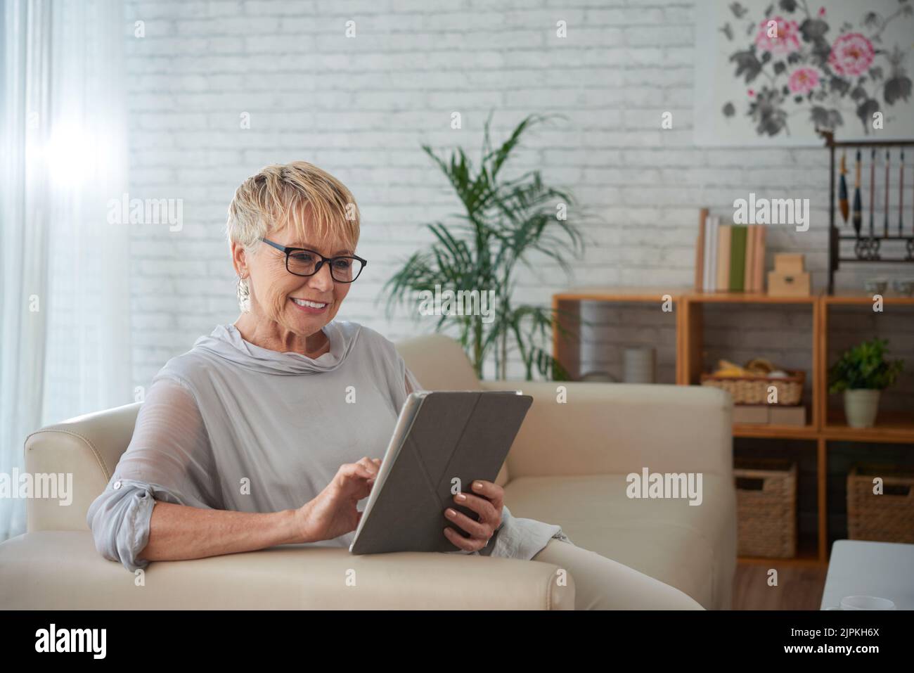 Smiling aged young woman using application on tablet computer Stock Photo