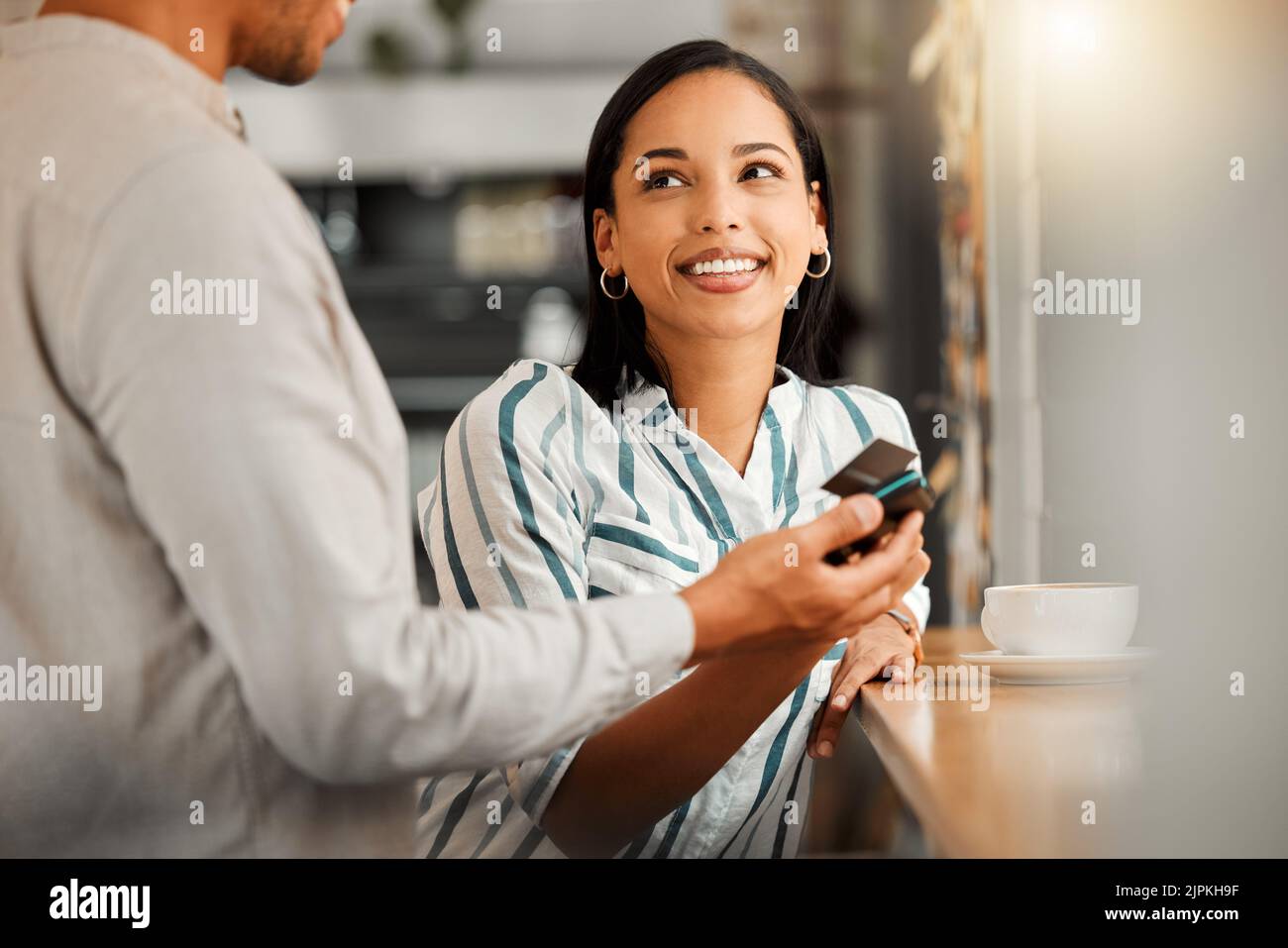 Customer paying using contactless credit card, standing by cafe or restaurant bar counter. Smiling woman make cashless payment for coffee bill with Stock Photo