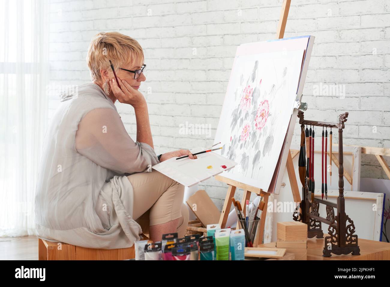 Talented creative aged woman looking at her work Stock Photo