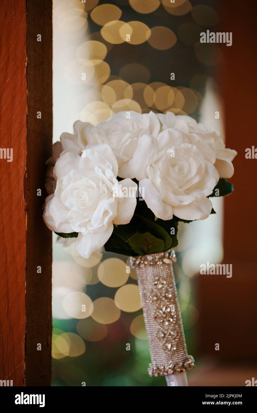 White artificial roses wedding bouquet. Bridal florals with decorative handle. Stock Photo
