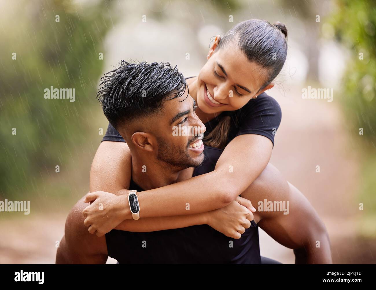 Wet, fitness couple playing in the rain during fun romantic outdoor training, running or healthy workout exercise in park. Happy sport people with a Stock Photo