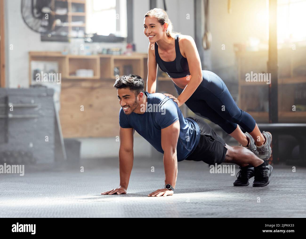 Fitness, strong and wellness couple exercising, training or workout exercise inside gym. Sporty professional woman and man or trainer doing pushup and Stock Photo
