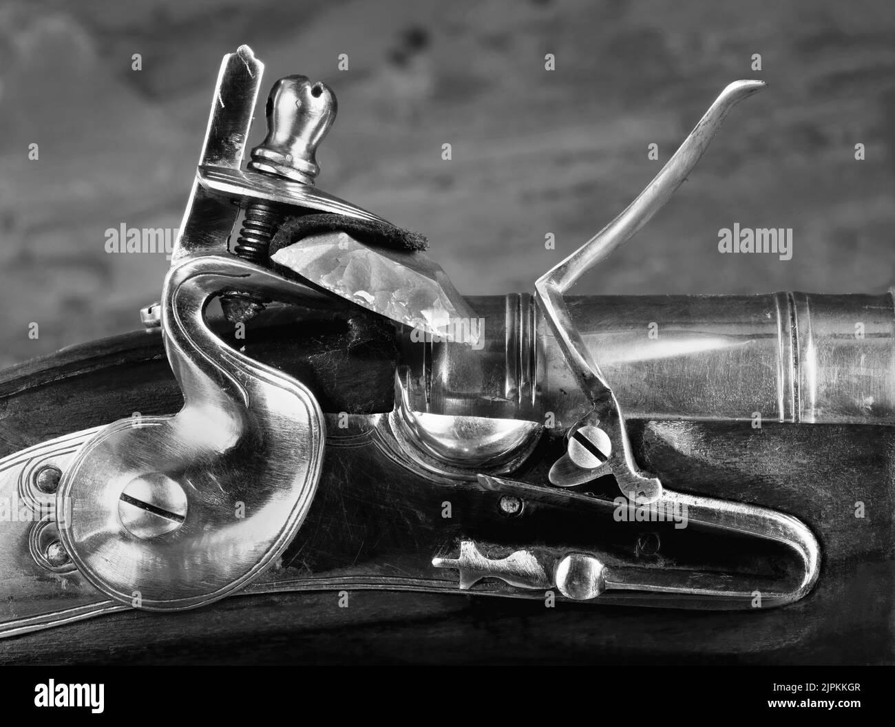 Closeup of antique flintlock gun showing the hammer ,flint , pan and frizzen in black and white. Stock Photo