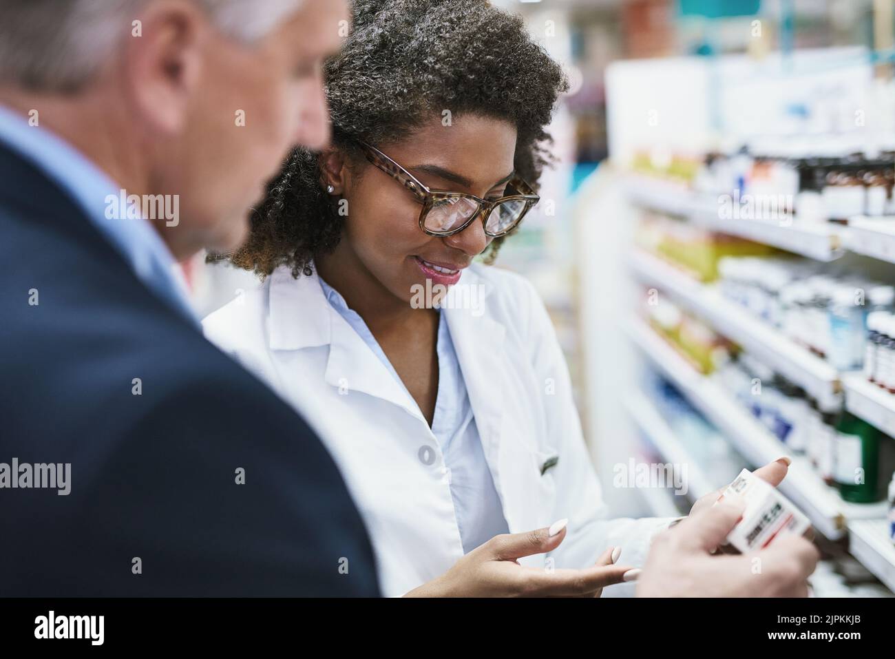 These work miracles. a helpful young female pharmacist helping a customer with choosing the right medication in the pharmacy. Stock Photo