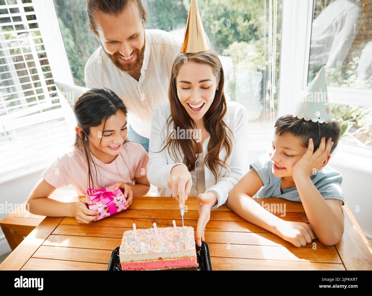 Birthday, cake and celebration with a family celebrating a mother on a special day. Cutting the dessert, having a party and spending time together Stock Photo