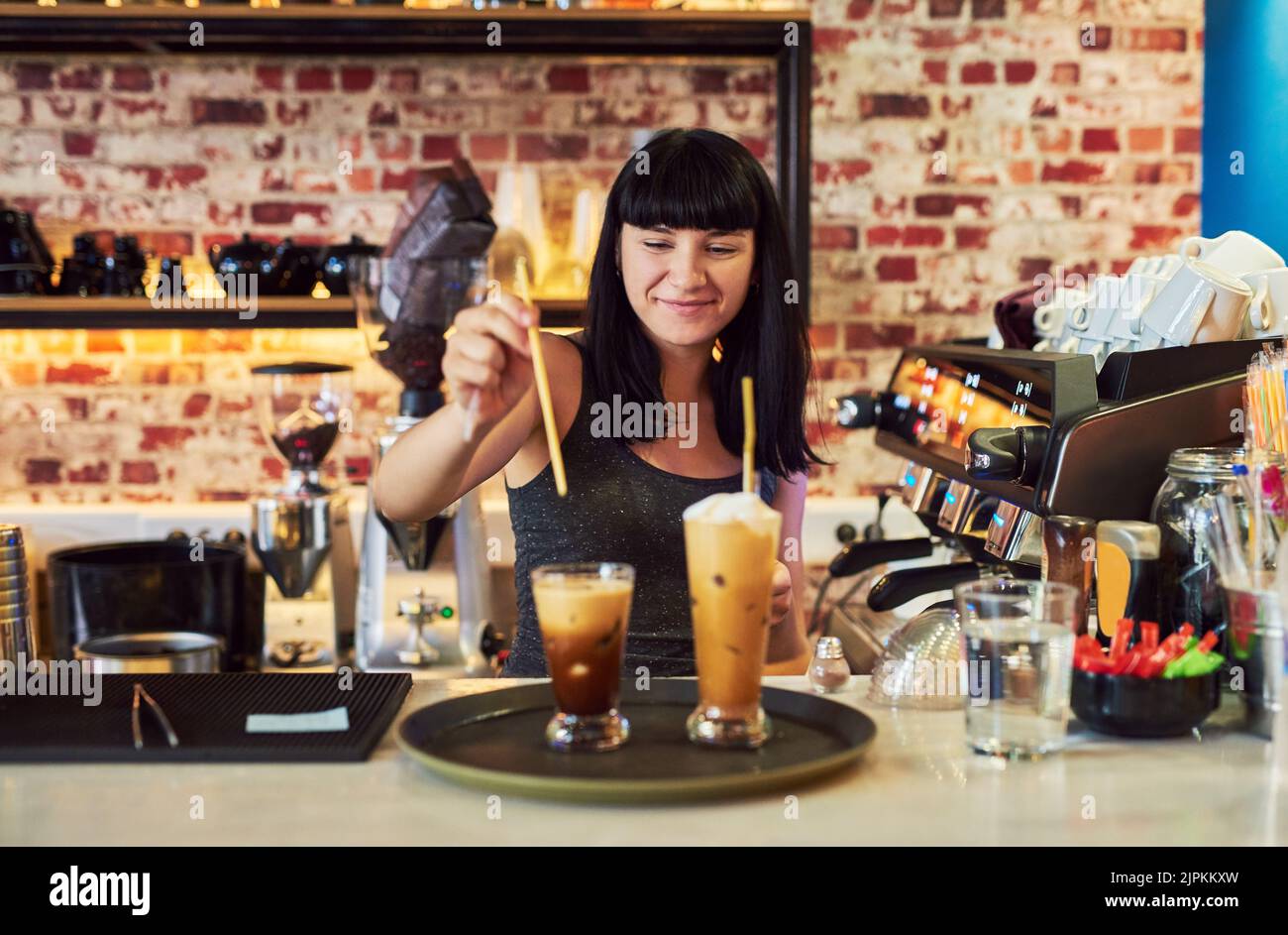 She can make you what you want. a young waitress working behind the counter at a bar. Stock Photo