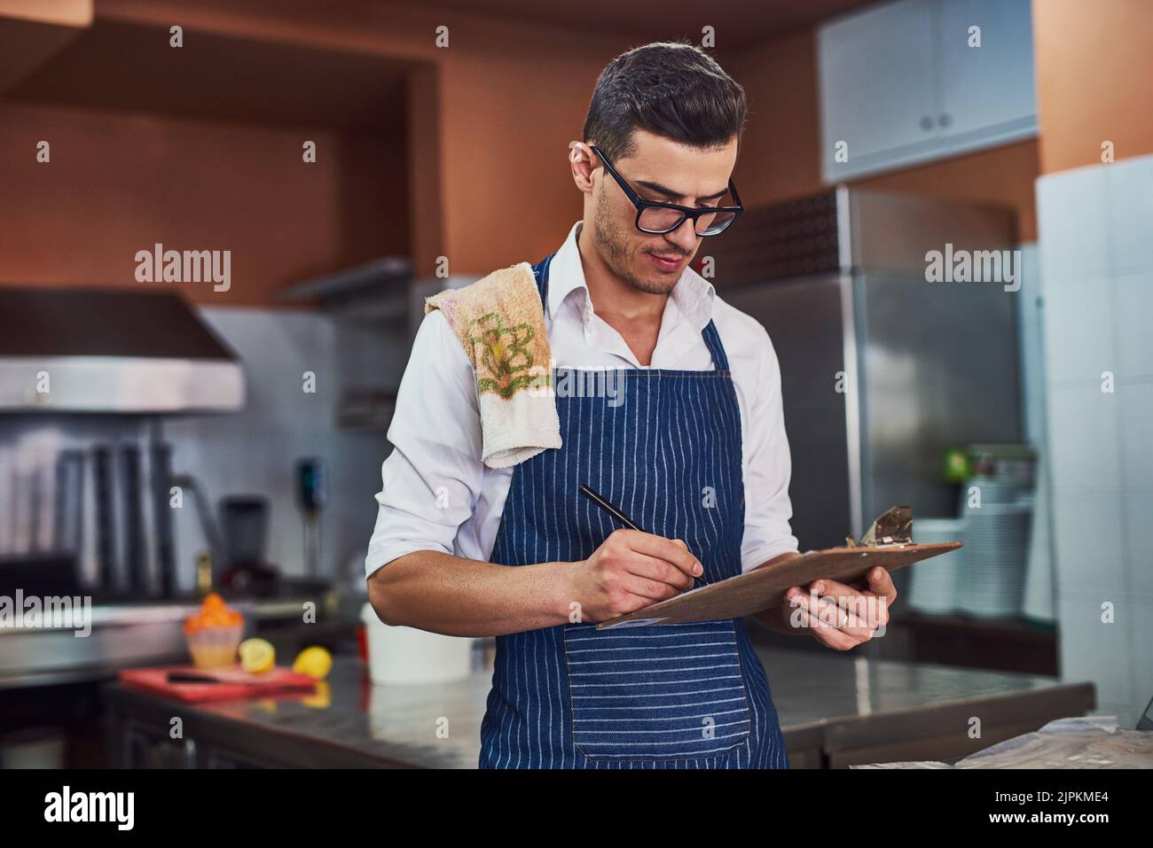 Time for the inventory checklist. a man working at a restaurant. Stock Photo
