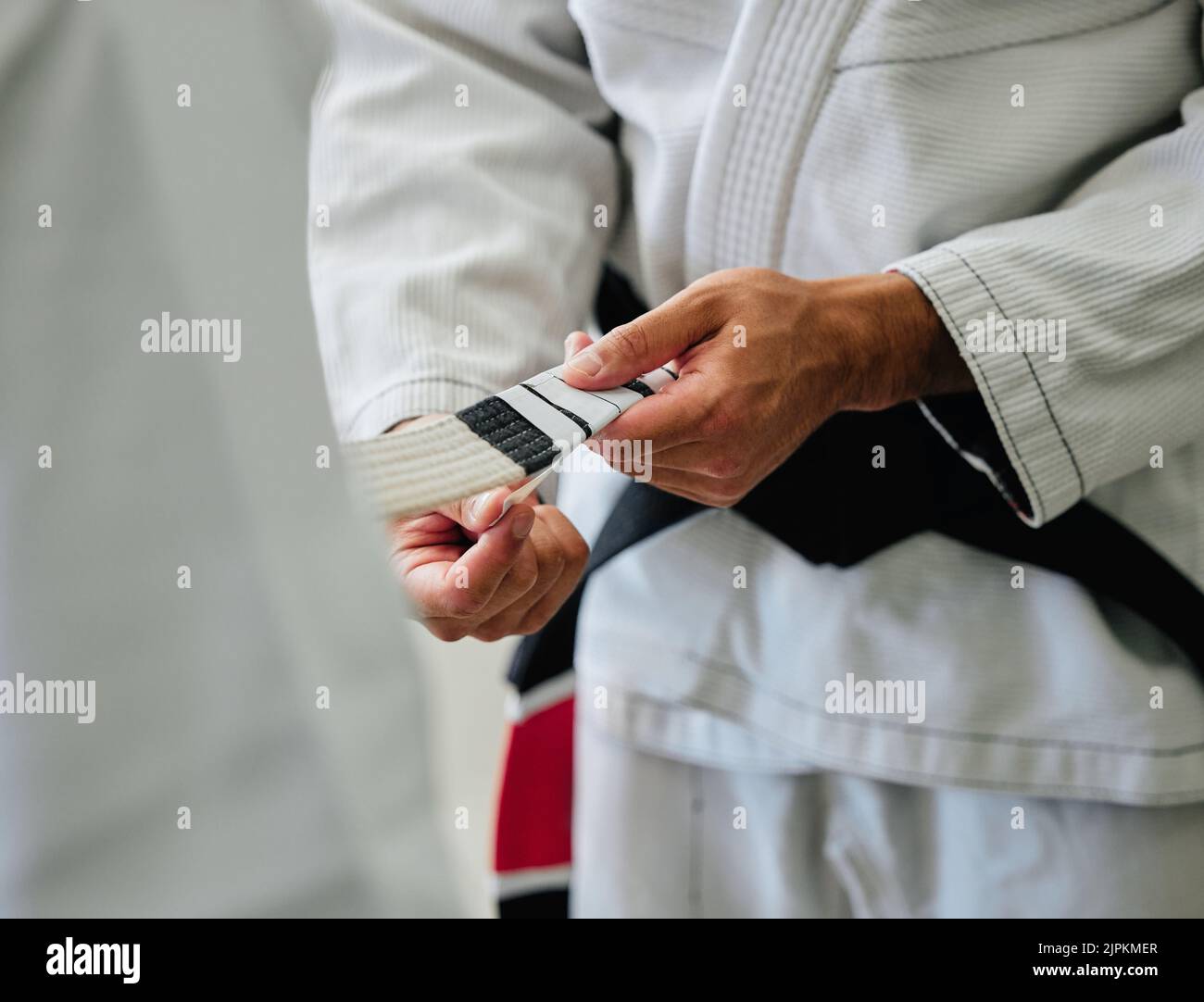 . Karate master tying a belt on a student in a dojo before practice