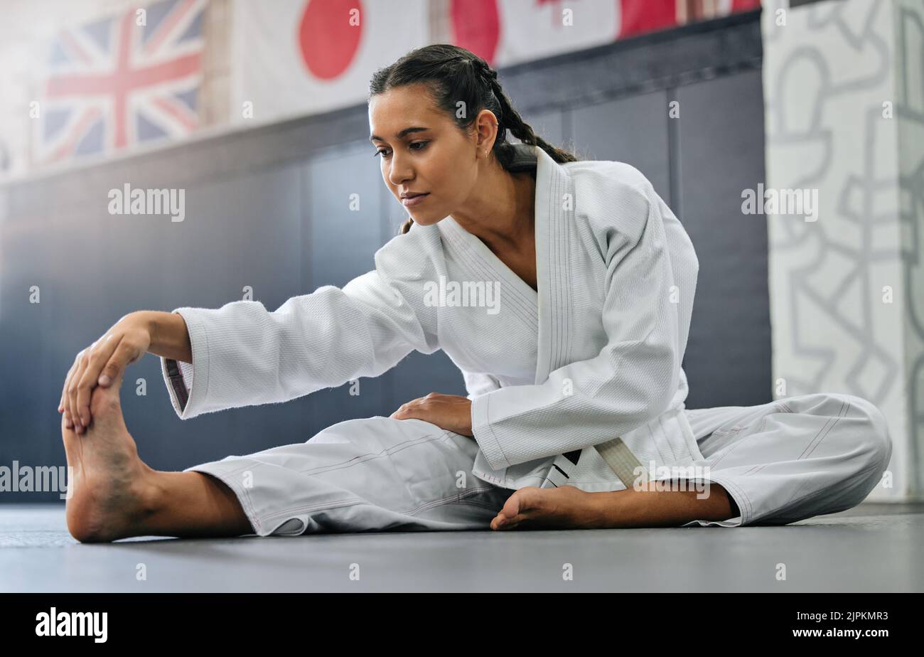 Exercise, fight and workout stretch of a karate school student with focus before training start. Sport woman or coach stretching for an exercise at a Stock Photo